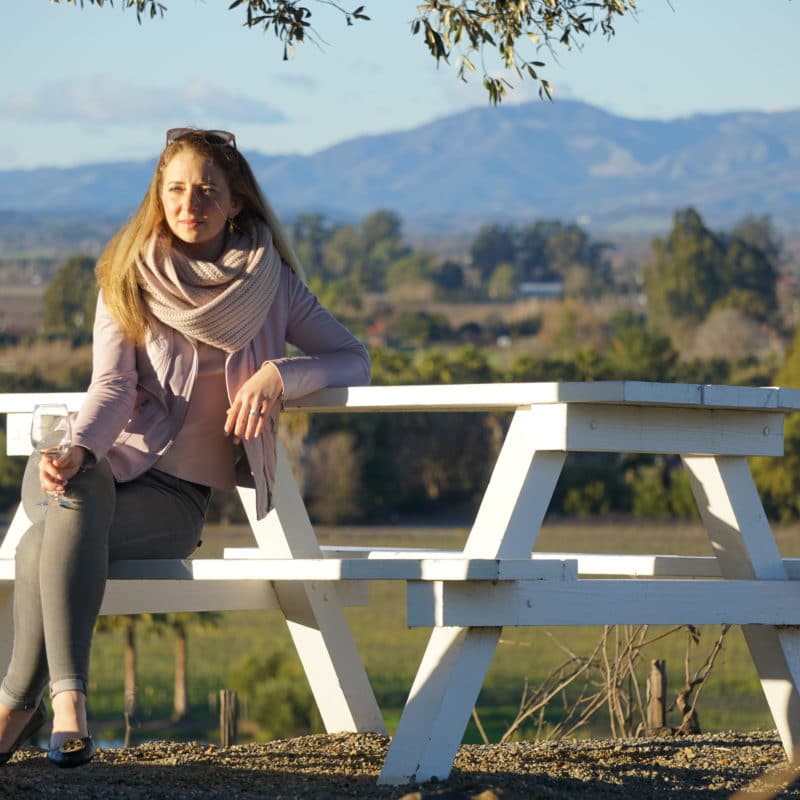Sitting with wine glass on picnic table enjoying the beautiful vineyards