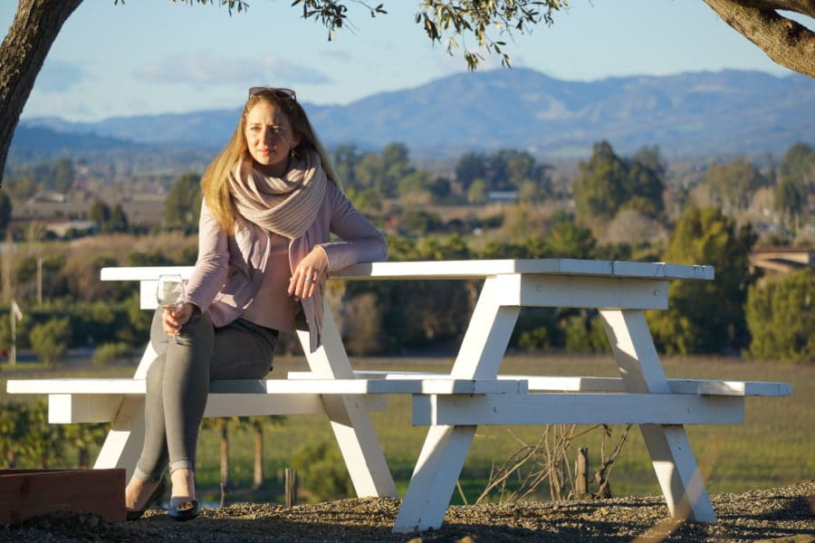 Sitting with wine glass on picnic table enjoying the beautiful vineyards